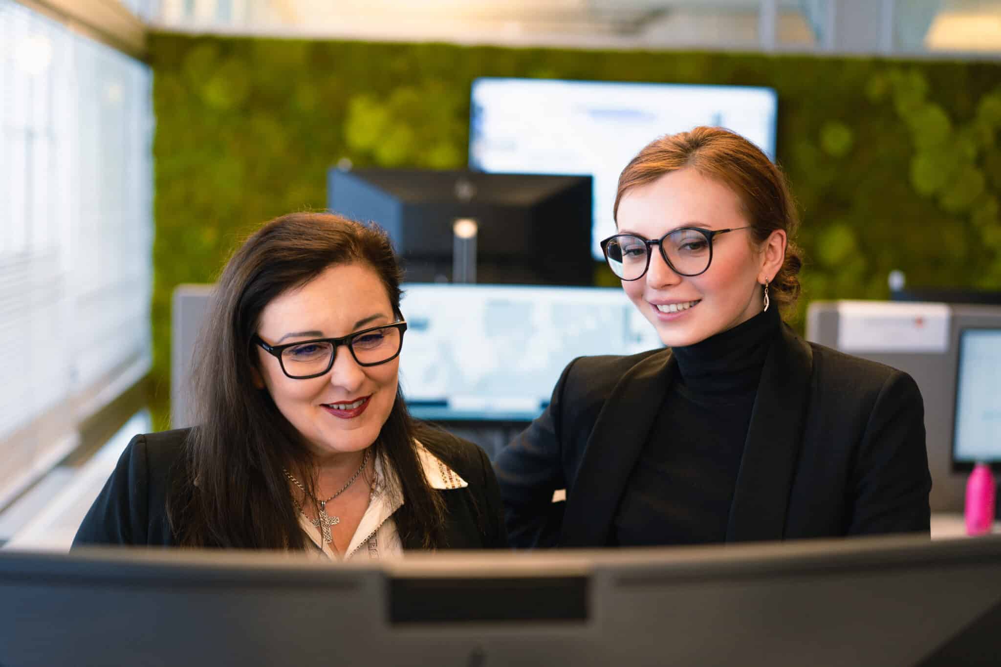 2 women behind a computer screen.